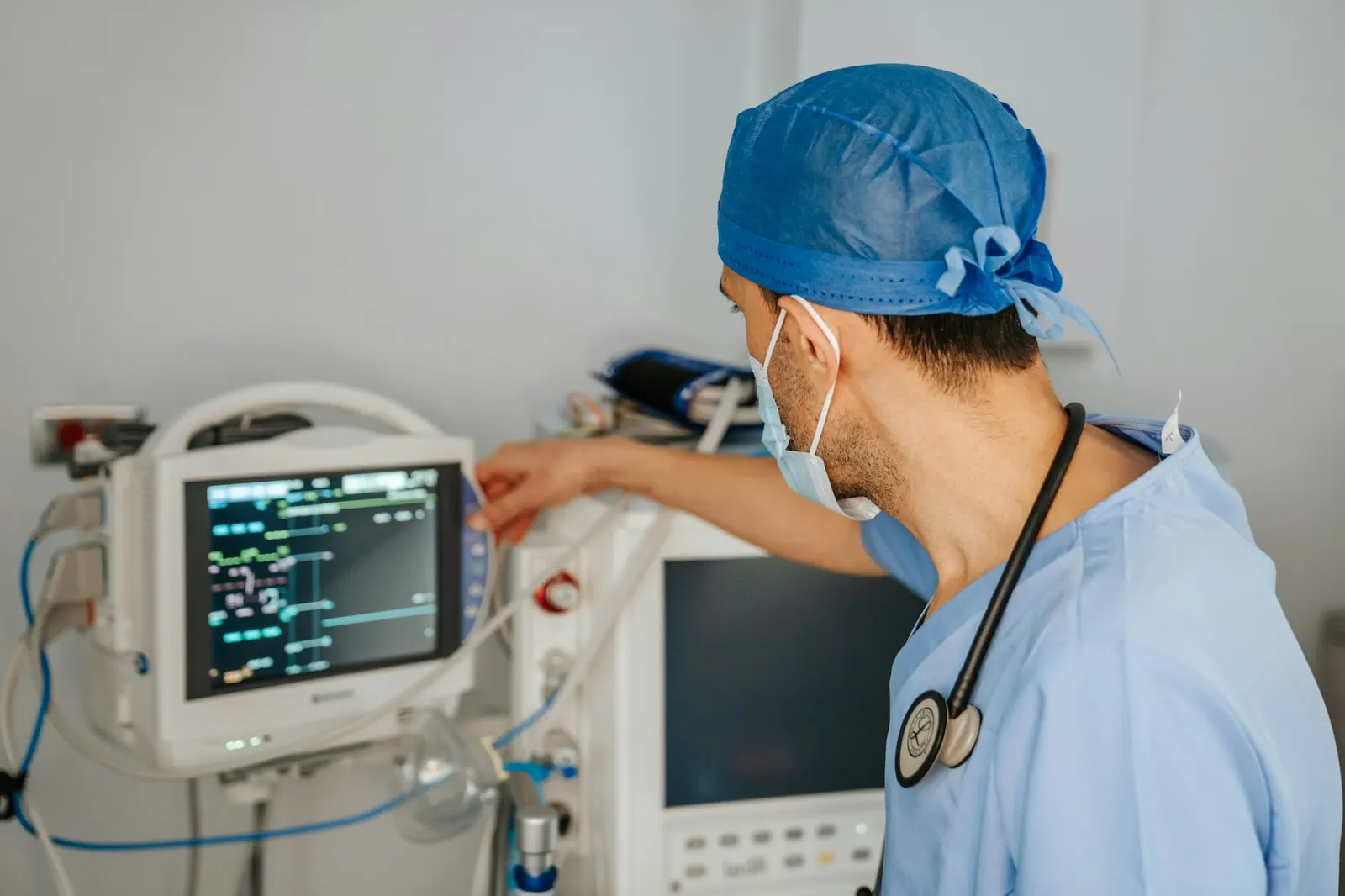 Clinician in scrubs adjusting the monitor on an anesthesia and ventilation workstation