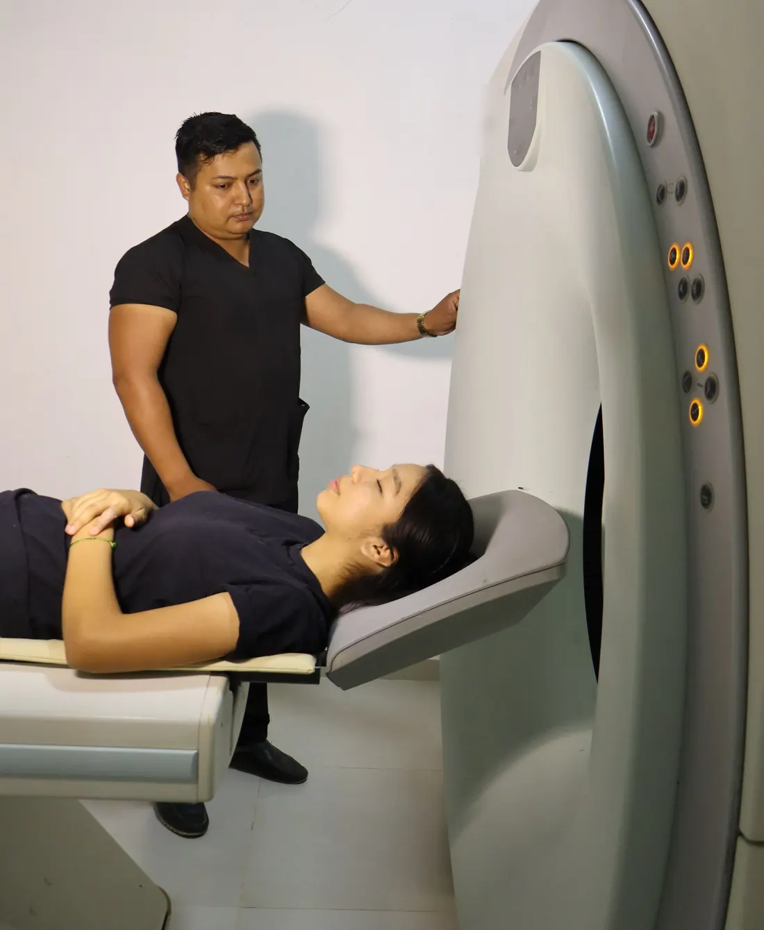 Technologist standing beside a CT scanner with a patient lying on the table