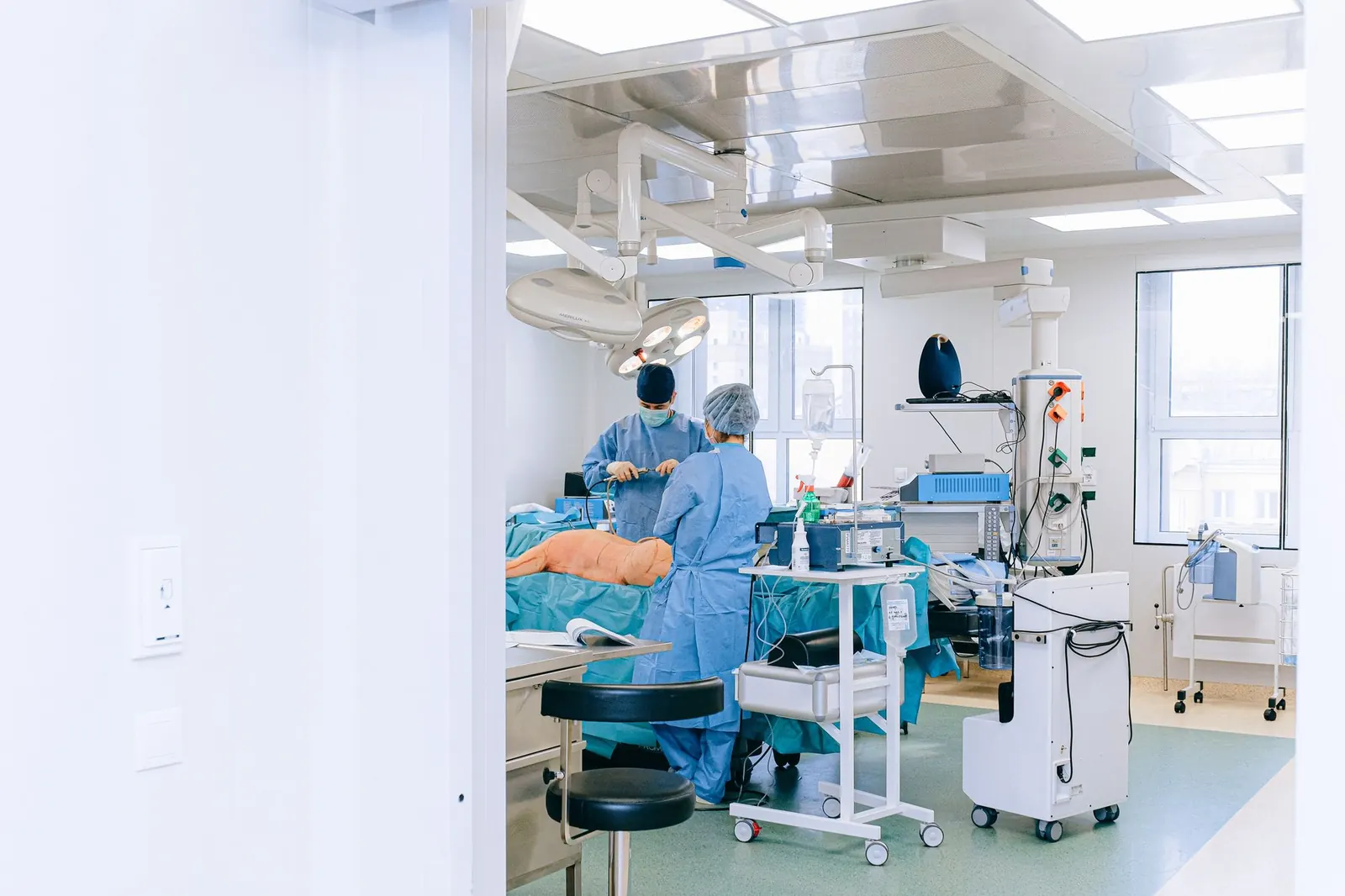 Bright operating room with a surgical team, overhead surgical lights, and equipment carts