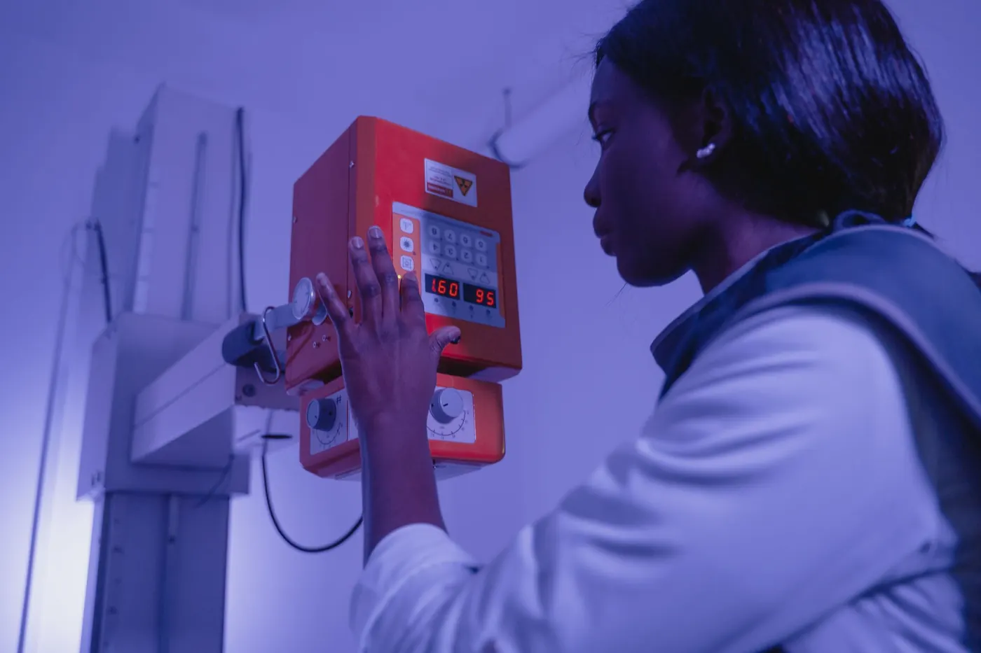 Radiology technologist in a lead apron adjusting an X-ray tube head